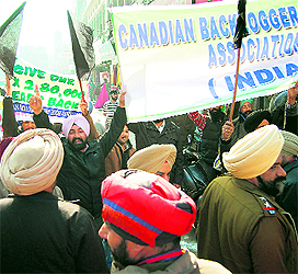 Members of the Canadian Backloggers Association show black flags to Canadian Minister of Citizenship, Immigration and Multiculturalism Jason Kenney (left) to protest against the delay in the processing of their visa applications, near the Golden Temple in Amritsar on Friday