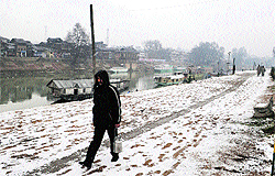 A man walks through a snow-covered road in Srinagar on Saturday