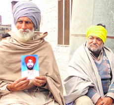 Bagga Singh shows the picture of his son who went missing on December 13, 2010. 