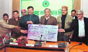 Chairman of the Forest Development Corporation Kunwar Pranav Singh presents a cheque for Rs 21 lakh to Chief Minister Vijay Bahuguna in Dehradun on Sunday.