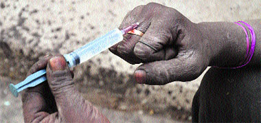 A labourer injects a drug into his hand to get a kick; and (right) a teenager inhales a drug-smeared handkerchief in Ludhiana.