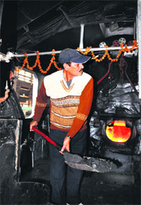 Railway employee puts coal to power the engine.