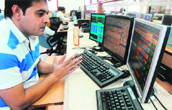 A stock dealer monitors share prices during intraday trading in Mumbai on Monday. The BSE Sensex rose 0.4% or 80.41 points to 19,986.82, crossing the key 20,000-point mark intraday after two years, on optimism of a rate cut as inflation eased this week.  AFP
