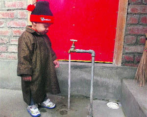 A child looks at a frozen water tap as night temperature dipped below freezing point in Srinagar on Wednesday. 