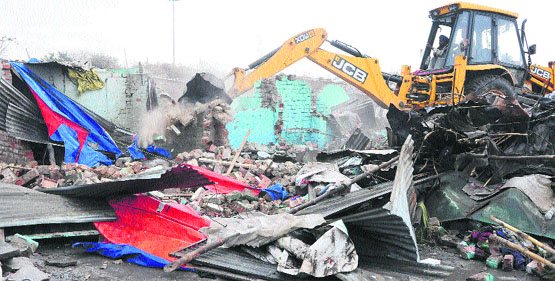 An earth-moving machine pulls down illegal tenements in Colony No 5 in Sector 50, Chandigarh, on Thursday. Tribune photo: Parvesh Chauhan