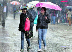Girls walk during heavy rain in Dehradun on Thursday.