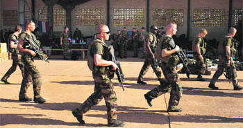 French soldiers walk past a hangar they are staying at Malis army air base in Bamako. France plans to increase its troops in Mali. 