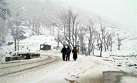 Locals trudge along a road in Qazigund on Thursday. The Jammu-Srinagar National Highway was closed to traffic due to heavy snowfall in the Valley