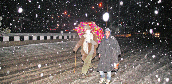 People walk at the City Centre in Lal Chowk area during snowfall in Srinagar on Thursday.