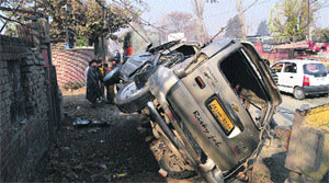 People look at a damaged vehicle after it was hit by a truck at Pampore on the Srinagar-Jammu National Highway.
