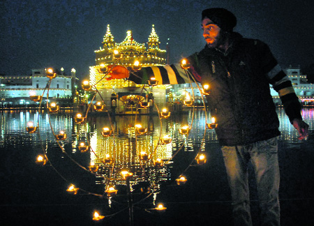  A devotee lights lamps at the Golden Temple celebrating the birth anniversary of Guru Gobind Singh in Amritsar on Friday. 