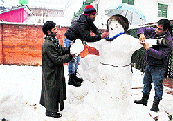 Residents make a snowman to celebrate the first snowfall of the season in Srinagar on Friday