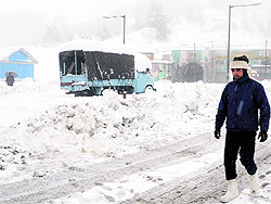 A traffic policeman walks near the Jawahar Tunnel during snowfall on the Jammu-Srinagar National Highway on Friday