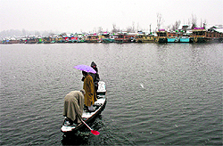 A boatman ferries people in a boat on the Dal Lake in Srinagar on Friday