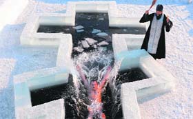 An Orthodox believer plunges into icy waters as a priest blesses him on the eve of the Epiphany holiday in Pilnitsa near Minsk in Belarus on Friday.