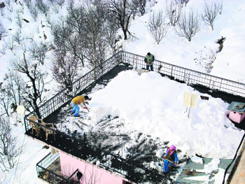 Residents clear snow from rooftops after a heavy snowfall near Manali on Saturday.