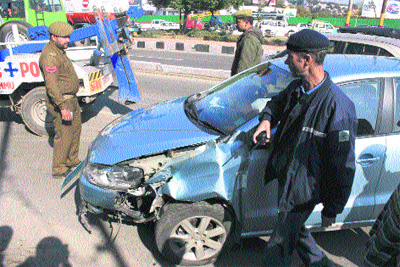 A policeman carries out investigations at the spot where a car rammed into a road divider on a flyover in Jammu on Saturday. 