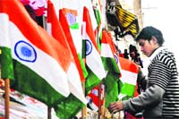 A shopkeeper arranges National Flags ahead of Republic Day in Jammu on Saturday.