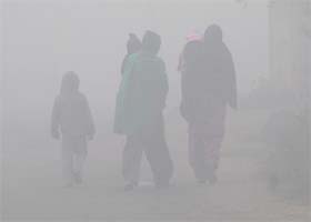 Blanket of haze: Women and children make their way through thick fog on the outskirts of Amritsar on Sunday
