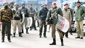Security personnel stand guard in front of closed shops during a shutdown in Srinagar on Monday