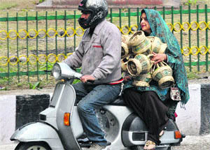 A couple carries kangris in Jammu on Tuesday. With the mercury still down, these traditional fire pots are still very much in demand. 