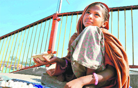 On National Girl Child Day, a girl, who should be going to school, sells food for fish at Har-ki-Pauri in Haridwar on Thursday. 