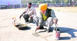 Workers repair the damaged floor at the Parade Ground in Sector 17, Chandigarh, on Friday.