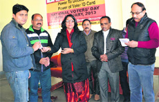 Reasi DEO Nirmal Sharma distributes election photo identity cards among new voters in Reasi on Friday.