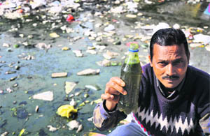 A man holds the water sample collected from Ranbir Canal, which has turned toxic due to dumping of garbage by residents in Jammu. 