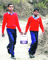  Students bring drinking water at Dera Bawa Middle School in Reasi. 