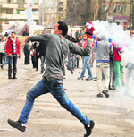 A protester prepares to throw back a tear gas canister fired by riot policemen during clashes near Cairos Tahrir Square on Sunday. 