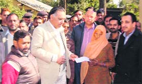 Minister for Transport and Technical Education GS Bali hands over financial assistance to an old woman of Kawari at Pathiar on Monday.