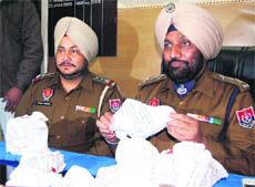 Police officials show weapons and narcotics seized from four members of a gang in Amritsar on Tuesday. 