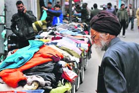 An old man looks at woollen clothes in a market in Jammu on Wednesday