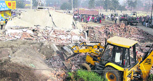 A JCB pulls down a newly constructed house on an encroached land in Sanjay Gandhi Colony in Jalandhar on Thursday.