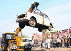 An unclaimed vehicle being lifted by MC workers at the Sector 28 motor market in Chandigarh on Friday.