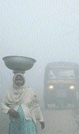 With headlights on, vehicles move at a snails pace on the busy GT Road in dense fog on Friday morning.