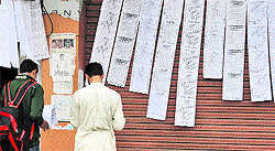 Job aspirants take a look at application forms at a shop in Dogra Chowk, Jammu on Friday