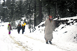 People walk towards their destination in the Rajwar area of Handwara, Kupwara district, on Friday