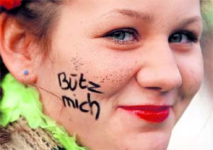 A girl, with the words kiss me on her cheeks, poses during the Cologne Carnival.