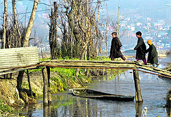 Children walk on a footbridge over the Dal Lake in Srinagar on Sunday
