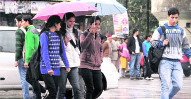 Girls protect themselves from rain in Dehradun on Monday. 