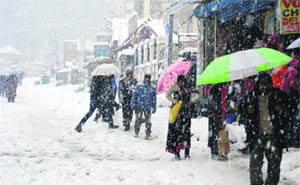 People walk on a snow-covered Mall road in Manali on Monday. 