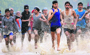 Candidates run on a water-logged track in rain during a physical fitness test at the Army recruitment rally in Karnal on Tuesday.