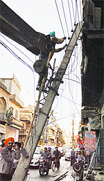PSPCL employees repair an electricity pole near Arya School in the Old City area of Ludhiana on Tuesday