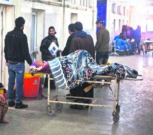 An attendant waits with patient in the corridor of SMHS hospital in Srinagar on Wednesday.
