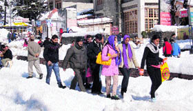 Tourists and local residents walk on the snow-covered Mall Road in Manali on Thursday.