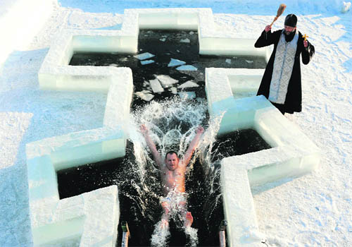 A Belarus orthodox believer plunges into icy waters as a priest blesses him on the eve of the Epiphany holiday in Pilnitsa, near Minsk.