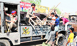 MC men de-load the confiscated material from a truck after the corporation decided to withdraw the anti-encroachment drive in Putlighar area in Amritsar in 2012