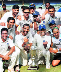 Victorious Rest of India team members strike a pose with the trophy on Sunday.
